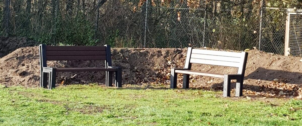 2 Bänke vor einem Erdwall auf einer Wiese