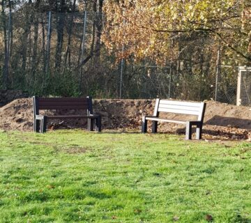2 Bänke vor einem Erdwall auf einer Wiese