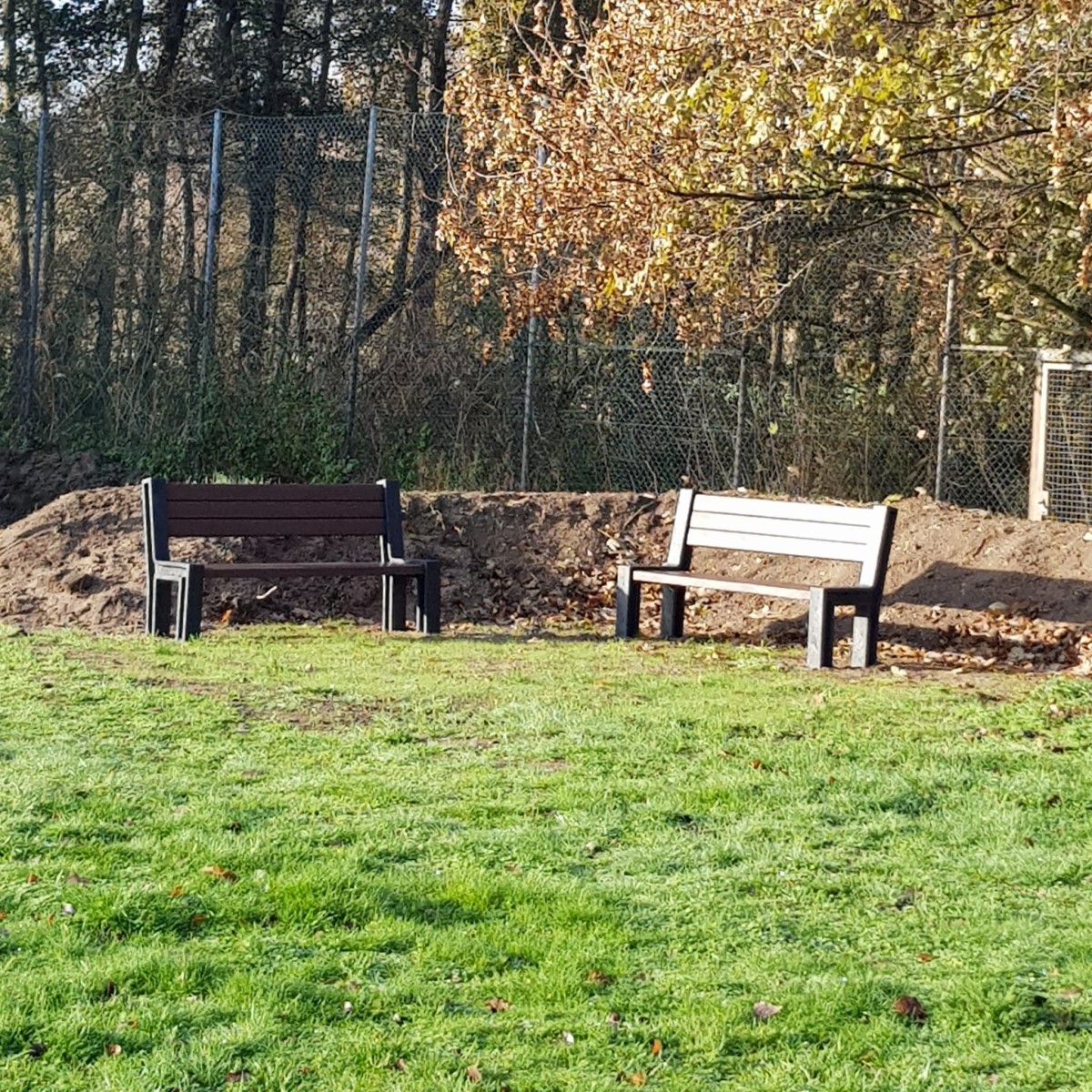 2 Bänke vor einem Erdwall auf einer Wiese