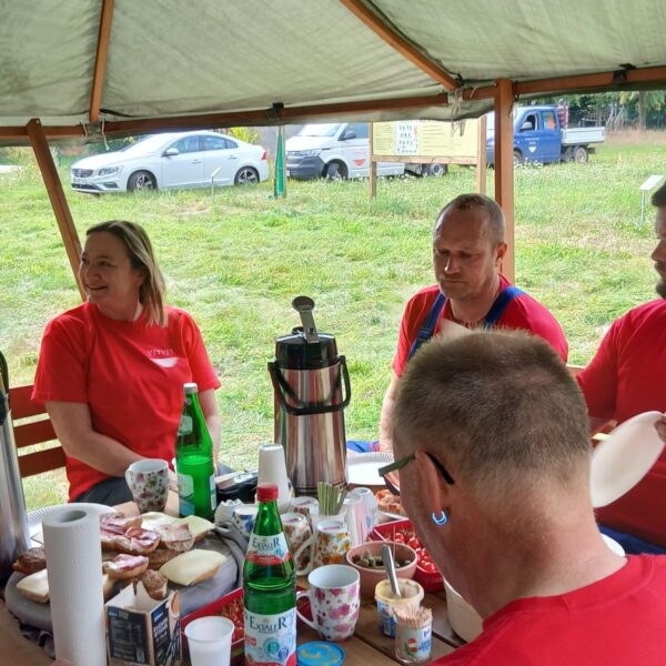 Eine Frau und 2 Männer sitzen am Tisch und frühstücken.