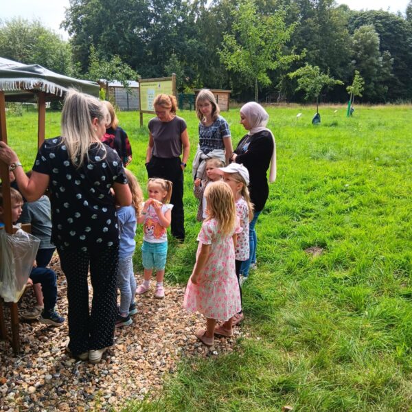 Einige Kindergartenkinder und Frauen stehen auf der Streuobstwiese
