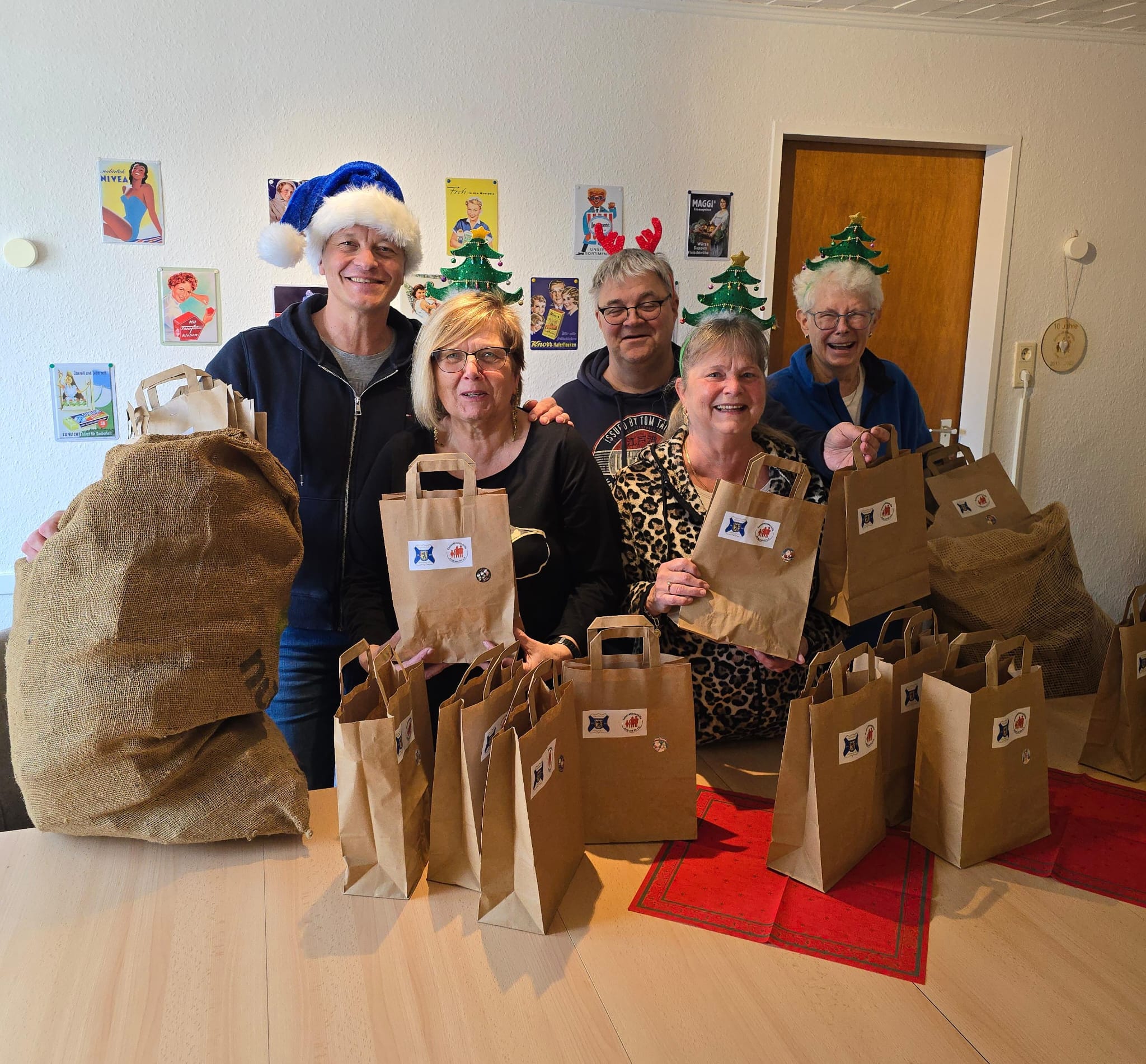 5 Frauen stehen hinter einem Tisch. Auf dem Tisch stehen gepackte Weihnachtstaschen.